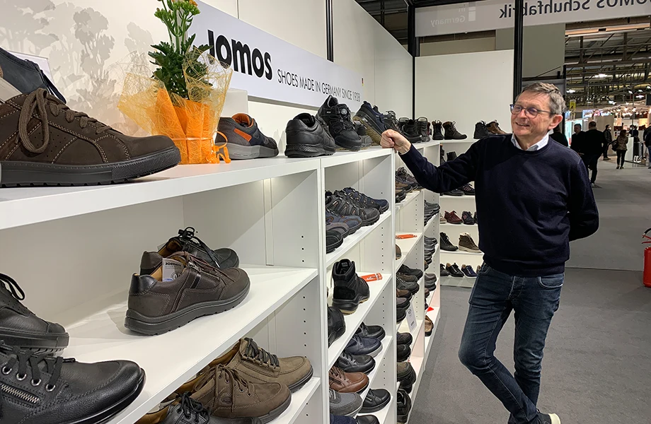 Herr Mohr am Messestand vor einem Schuhregal